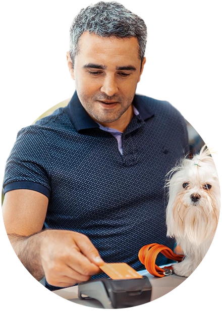 homem realizando pagamento com cartão, ao lado de um cachorro